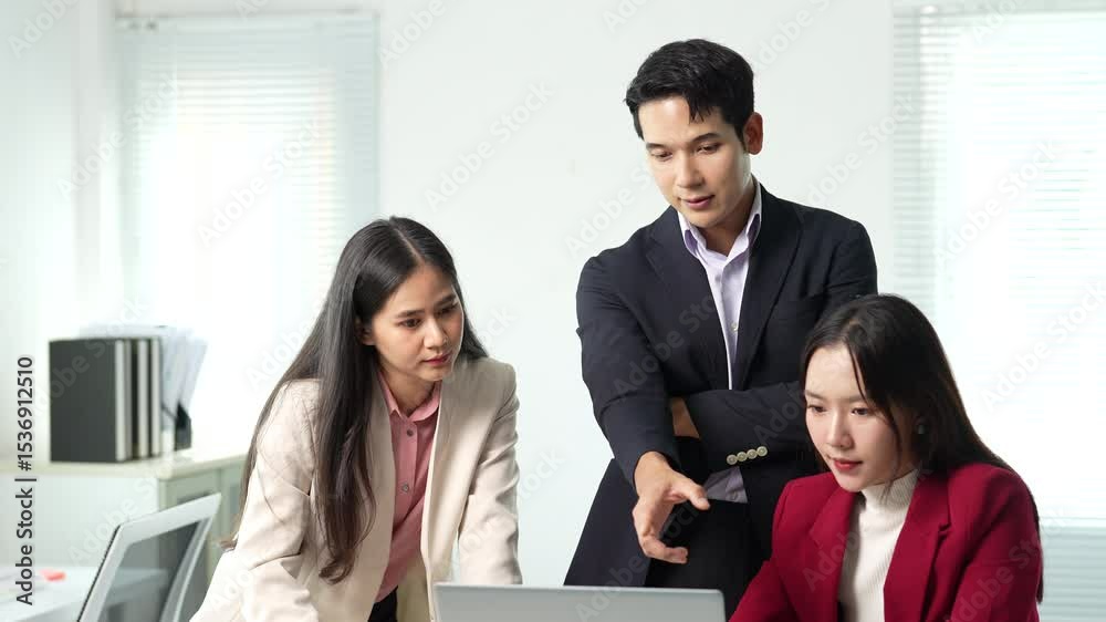 Professional Asian business team collaborating and sharing strategic insights while examining work details together using laptop in modern bright office environment Professional Asian business team collaborating and sharing strategic insights while examining work details together using laptop in modern bright office environment