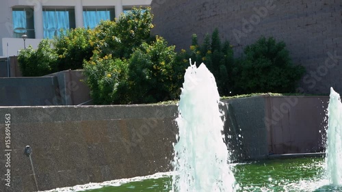 refreshing water fountain in the park in summer during hot weather and scorching sun. Bright blue and turquoise water with bubbling splashes quenches thirst
