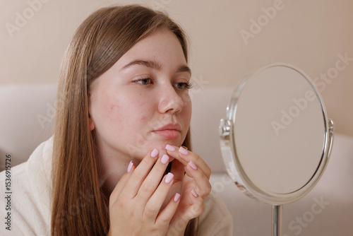 Bilde på lerret Teenage girl with acne examines her face in the mirror, highlighting skin imperfections and concerns about blemishes, skincare routine, and the challenges of adolescent skin health