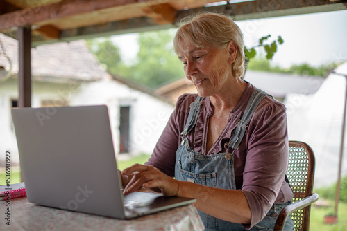 Senior woman working on laptop. 
Beautiful elderly woman with a laptop in the garden.