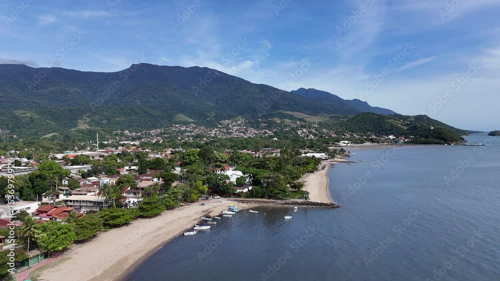 Imagem aérea da Praia Barra Velha em Ilhabela, com mar calmo, areia branca e vegetação tropical ao redor