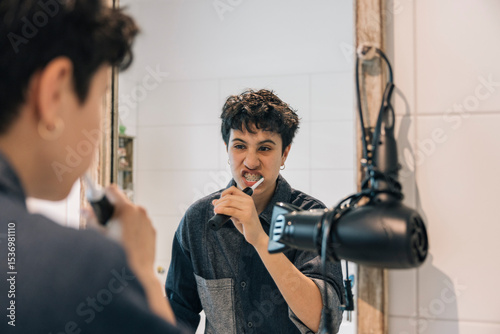 Teenager girl brushing teeth in bathroom mirror during morning routine