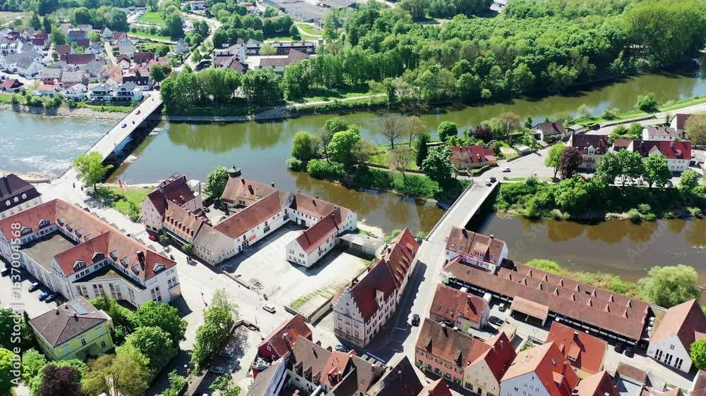 Luftaufnahme von Donauwörth mit roten Dächern, historischen Gebäuden und einem markanten Turm, eingebettet in eine grüne Landschaft. Die Stadt bietet eine charmante Kulisse. Donauwörth, Schwaben,