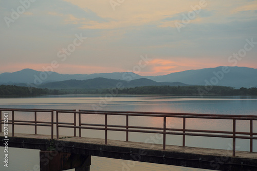 The concrete walkway into the water reservoir with the horizontal line of the mountains during the sunset
