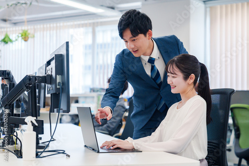 先輩に仕事を教えてもらう若い女性の会社員