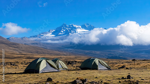 Colorful tents rest on Shira Plateau with snowy Kilimanjaro summit beyond.