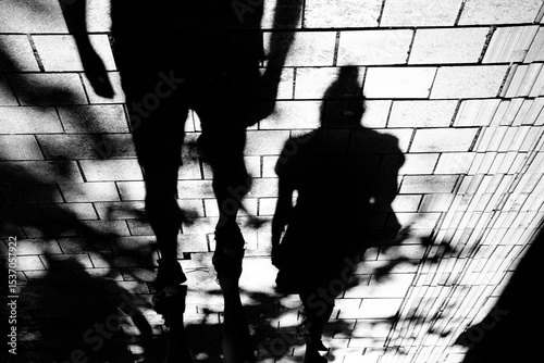 Shadow silhouette of man and women walking city street sidewalk in black and white high contrast