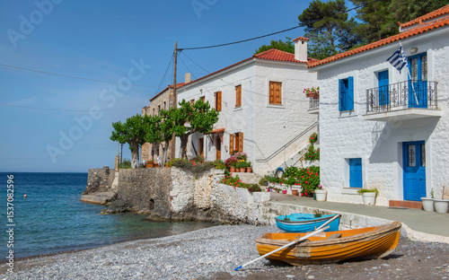 white house with colorful shutters of a seaside village with boats on the bea...