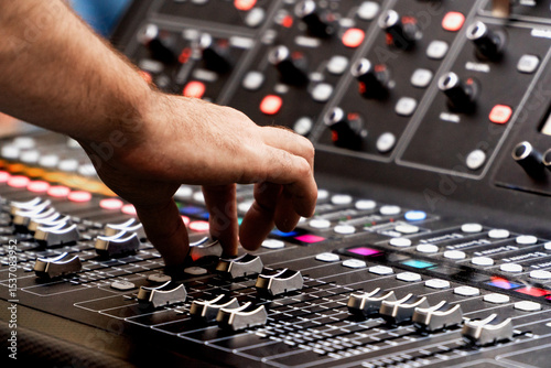 Close up of sound technician moving faders of the soundboard during a summer music festival