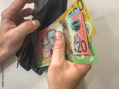 close up man hand holds wallet with AUD Australian dollar paper money on white isolated background