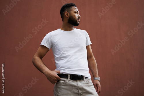 Portrait of stylish african american man in white t-shirt standing near building