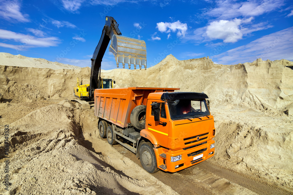 Obraz premium Excavator Loading Dumper Truck