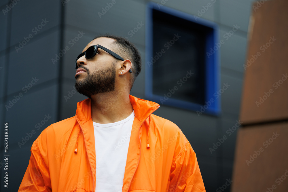 Fototapeta premium African american man in sunglasses and bright windbreaker posing on street