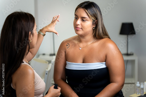 Beautician gesturing while examining client's eyebrows for lamination treatment