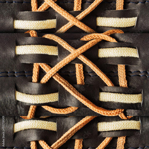Seamless 4k photo texture material of black leather with biege rope lacing inserts pattern.