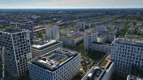 Aerial view of modern buildings near Hirschgarten in Munich, Germany, featuring green rooftops, residential towers, and office blocks surrounded by trees and urban infrastructure. 30 September 2024.