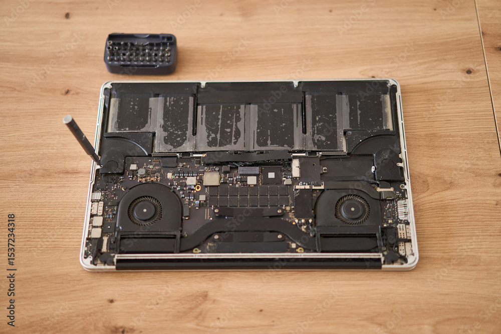Fototapeta premium This is a closeup view of a disassembled laptop along with various repair tools arranged on a wooden table