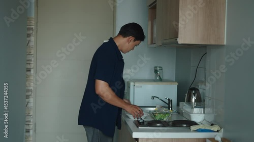 Young adult standing on kitchen counter carefully cutting fresh vegetables and preparing a nutritious salad
