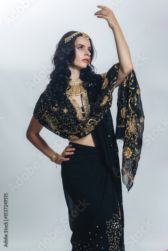 Принти на полотні A young brunette woman in a black Indian sari on a white background, full-length