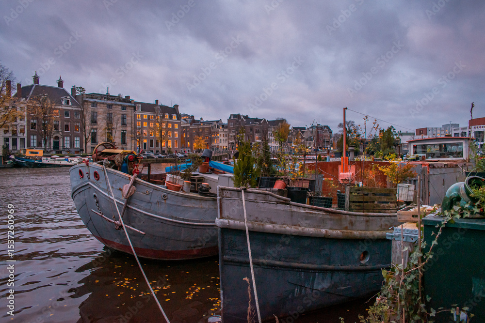 Obraz premium Boats filled with various items, plants, plant pots, pallets, and other supplies.