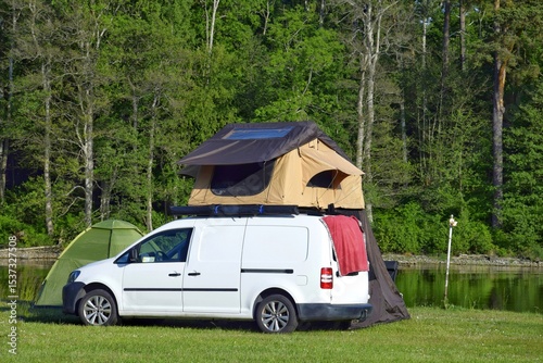 Picturesque campsite by the lake, tents are set up near the car and on the car. Family vacation in nature.