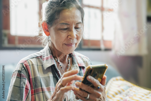 An elderly woman engages with her smartphone, highlighting technology's role in modern daily life.