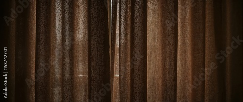 Closed brown fabric curtains with soft light filtering through in a dimly lit interior setting