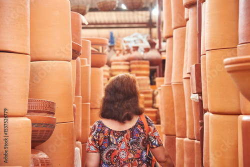 Unknown person walking in an aisle formed by stacks of ceramic pots in a store in Raquira, Boyaca, Colombia, a tourist town known for its craftsmanship and its pottery.