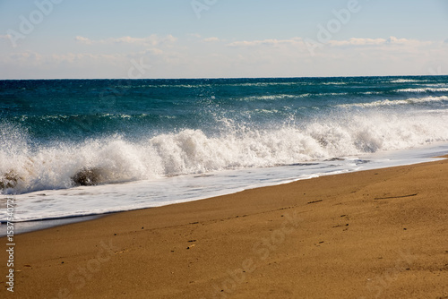 Fototapeta Naklejka Na Ścianę i Meble -  Sea wave breaks on sandy beach with clouds sky on Mediterranean coast of Mersin province, Atakent