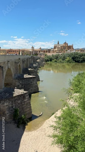 cordoba, spain - ancient roman bridge puente romano de cordoba over guadalquivir river with view of mezquita mosque cathedral in the background