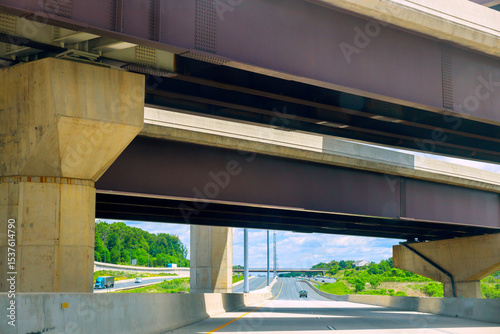 Φωτογραφία American highway bridge towers over lower roadway with green landscape in background vehicle traffic visible
