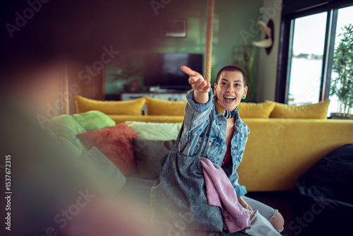 Happy woman reaching out while sitting on colorful couch at home