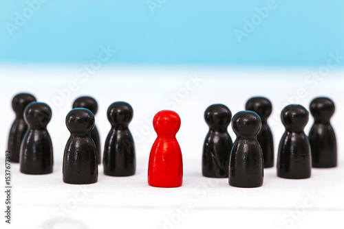 One red pawn standing amidst group of black pawn on blue background for different thinking ideas and leadership concept