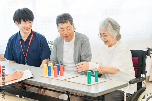 介護施設・リハビリ施設で働く作業療法士の職員とリハビリをするシニア女性
