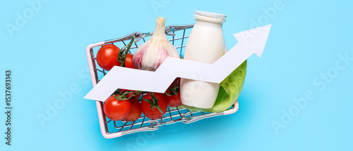 Shopping basket with products and arrow on blue background. Concept of rising price
