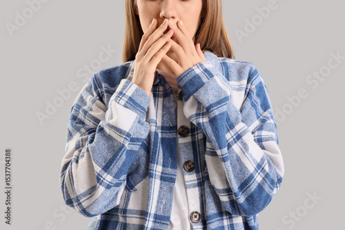 Worried young woman on grey...