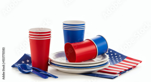 Studio photo of patriotic table decorations for 4th of July celebrations: stack of plastic cups, paper plates, and utensils in red, white, and blue colors, with American flag napkins neatly folded, al