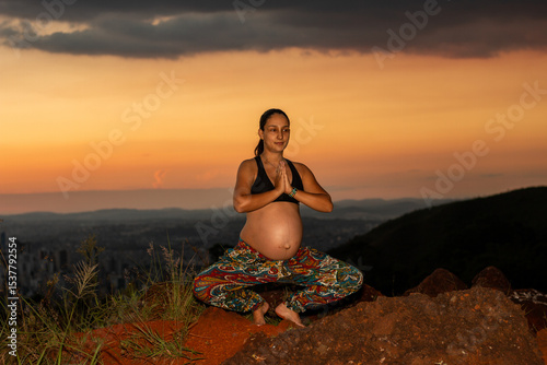 Mulher grávida fazendo Yoga no pôr-do-sol photo