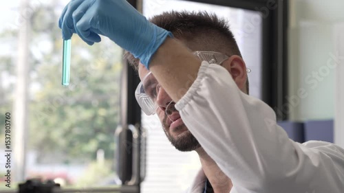 Young Caucasian male scientist works in laboratory, analyzing chemical samples with glassware and microscope. research tools, experiments, data interpretation, pharmaceutical development.