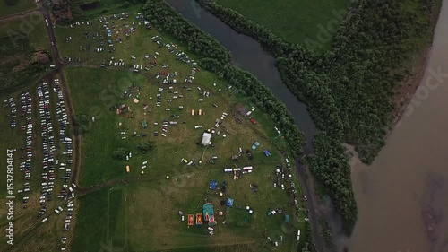 Drone View of an Local Outdoor Festival with Tents and Cars Parked Next to a River. Summer Event Footage.