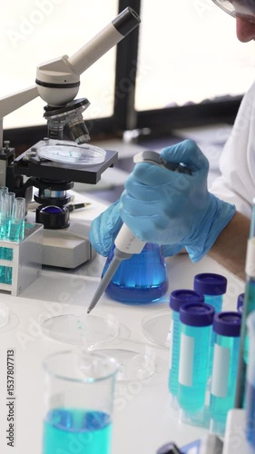 Young Caucasian male scientist works in laboratory, analyzing chemical samples with glassware and microscope. research tools, experiments, data interpretation, pharmaceutical development.