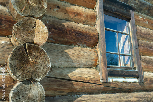 An old rustic house made of dark logs. An old wooden manor house. Logs for the house. The surface of the tree. Round cracked logs.