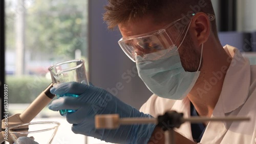 Young Caucasian male scientist works in laboratory, analyzing chemical samples with glassware and microscope. research tools, experiments, data interpretation, pharmaceutical development.