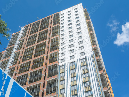 Construction work on the exterior cladding. Laying waterproofing material on the walls of a high-rise building. Insulation of the house. Balconies of a house under construction.