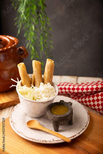 Flautas Ahogadas (Drowned Flautas) Golden tacos made with fried corn tortillas, filled with chicken or beef, and served in a glass or cup containing salsa or broth, lettuce, sour cream, and cheese.