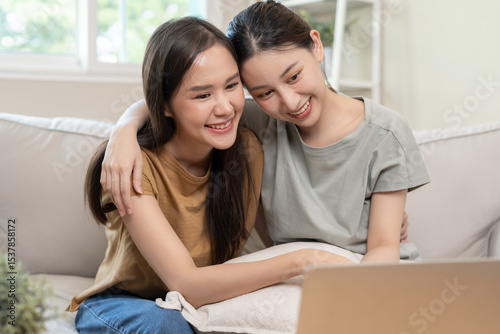 LGBT group. Good looking lesbian couples smile use computer at home on holiday. Asian young couple hug each other happily, lover in love, bisexualities, homosexuality, liberty, expression, happy life