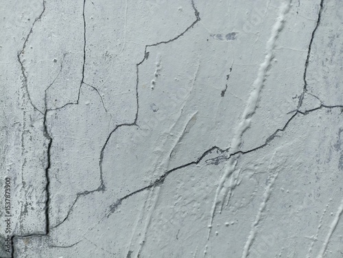 Cracked White Concrete Wall Texture. Close-up of a white painted concrete wall with visible cracks and rough surface texture, showing signs of aging and weathering photo