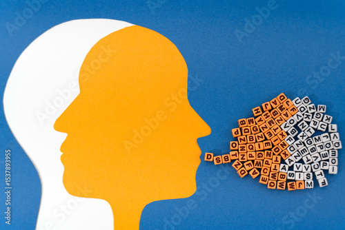 Two intersecting paper-cut heads, white and yellow, with contrasting letter patterns in the brain area. A cloud of mixed letters flows from the white mouth, symbolizing the contrasting moods  