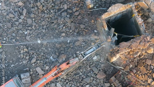 Excavator with hydraulic hammer dismantling a building at a construction site
