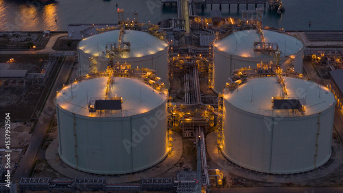 LNG storage tanks and terminal facility at dusk, showcasing large cylindrical containers, offshore piers, and cargo ships. Industrial landscape representing global liquefied natural gas